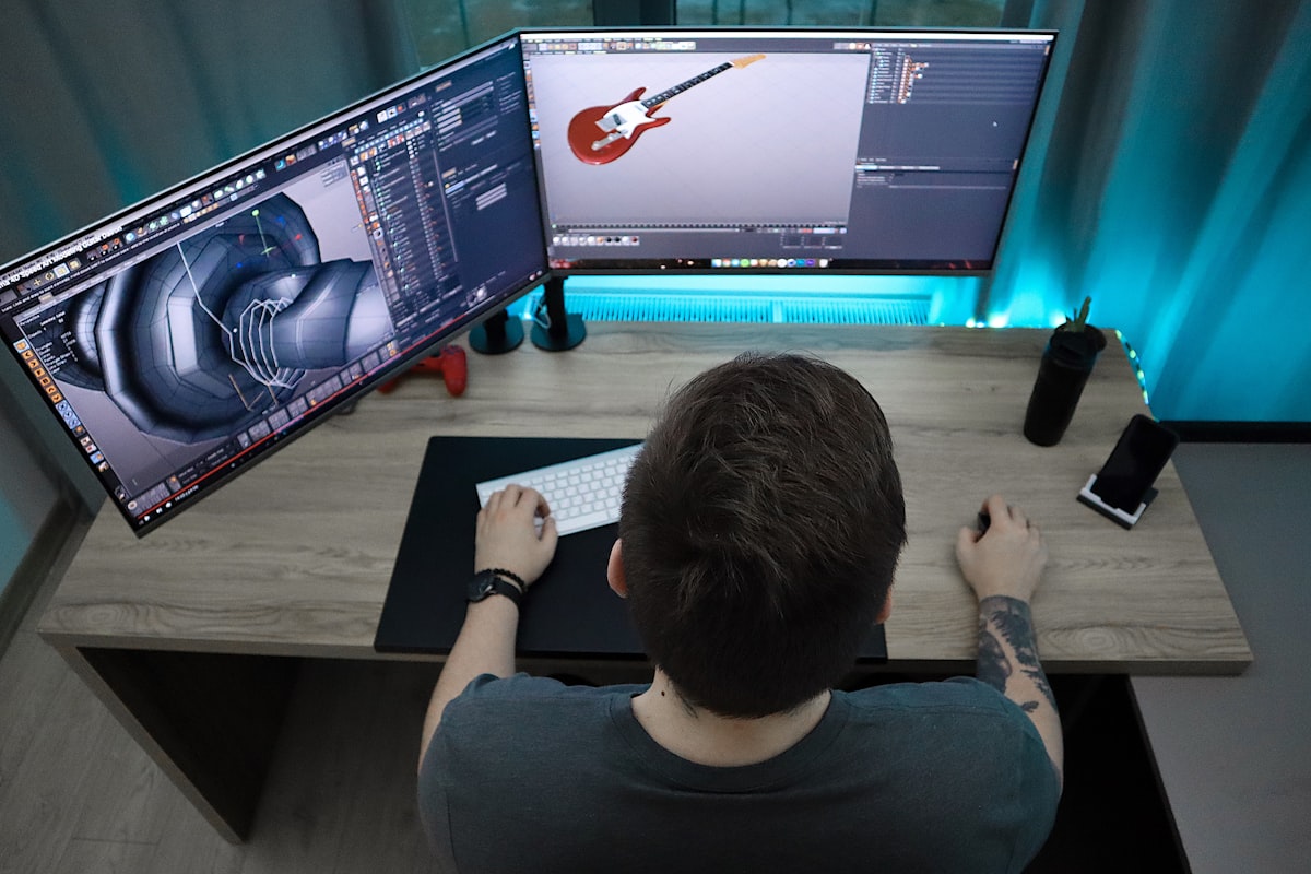 Infographiste 3D modélisant un objet sur deux écrans dans un studio